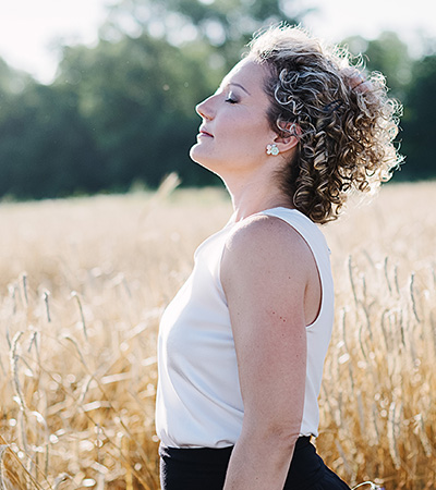 Woman in a field feeling calm and at peace after undergoing trauma therapy for her PTSD