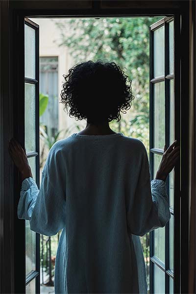 Woman looking out the window contemplating whether EMDR therapy or CPT trauma therapy is right to treat her PTSD