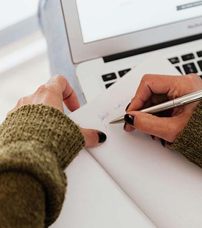 Woman writing an example of out of network reimbursement for her trauma therapy