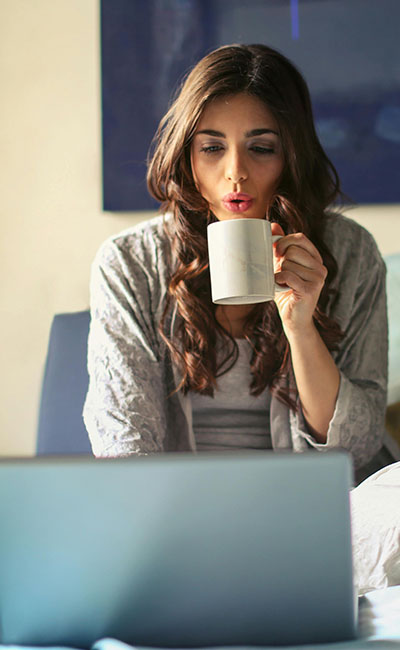 A woman sitting comfortably with a warm drink speaking with her telehealth therapist about her trauma from sexual assault