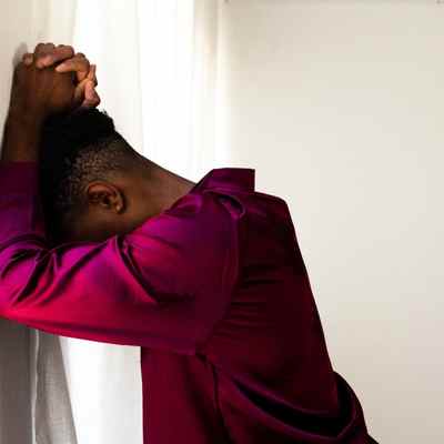 A Black woman stands with her head and arms against a wall, overwhelmed with her trauma A Black woman stands with her head and arms against a wall, overwhelmed with her trauma