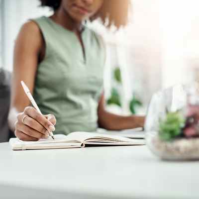 A Black woman writes in her notebook after her telehealth CPT therapy session, working on her assignment for the week A Black woman writes in her notebook after her telehealth CPT therapy session, working on her assignment for the week