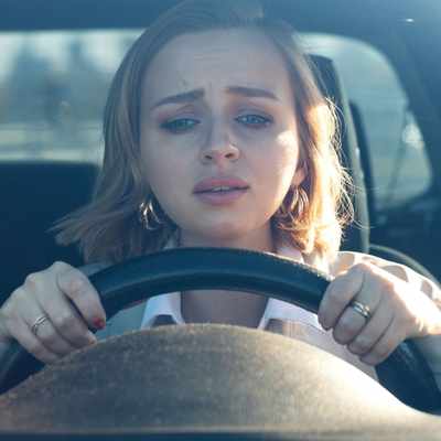 A woman stares out from behind the steering wheel of her car struggling with PTSD misdiagnosed as anxiety