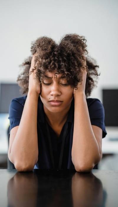 A woman holds her head in her hands struggling with hypervigilance and dissociation