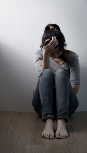 A woman sitting on the floor with head in her hand struggling with emotional numbness and other hidden trauma signs A woman sitting on the floor with head in her hand struggling with emotional numbness and other hidden trauma signs