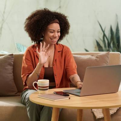 A woman waving at a laptop at the start of a therapy intake session