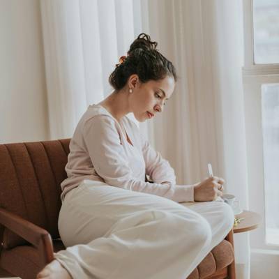 A woman writing while sitting in a chair documenting after a therapy intake session