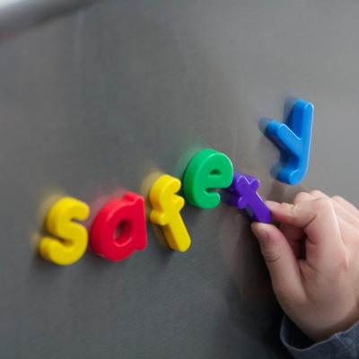 A child spells safety with magnetic letters to illustrate how people pleasing can start as a safety response called fawning that follows us into adulthood so we don't learn how to set boundaries