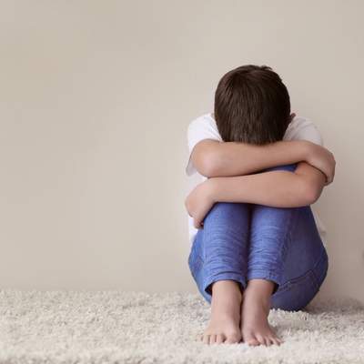 A child alone sitting curled up from childhood developmental trauma